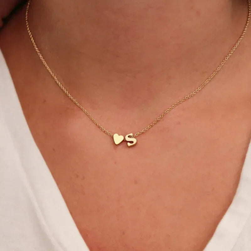Collana minimal con piccolo ciondolo a cuore e lettera personalizzata, disponibile in oro o argento. Un accessorio delicato perfetto come regalo elegante per lei.