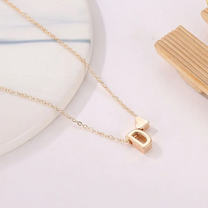 Collana minimal con piccolo ciondolo a cuore e lettera personalizzata, disponibile in oro o argento. Un accessorio delicato perfetto come regalo elegante per lei.